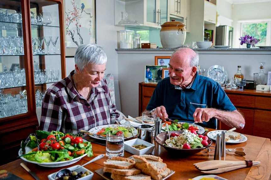 An elderly couple eating dinner with lots of vegetables
