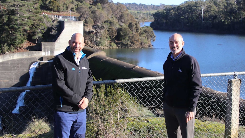 David Ikedife and Guy Barnett standing in front of the Trevallyn Dam wall and new eel bypass on a sunny winters day