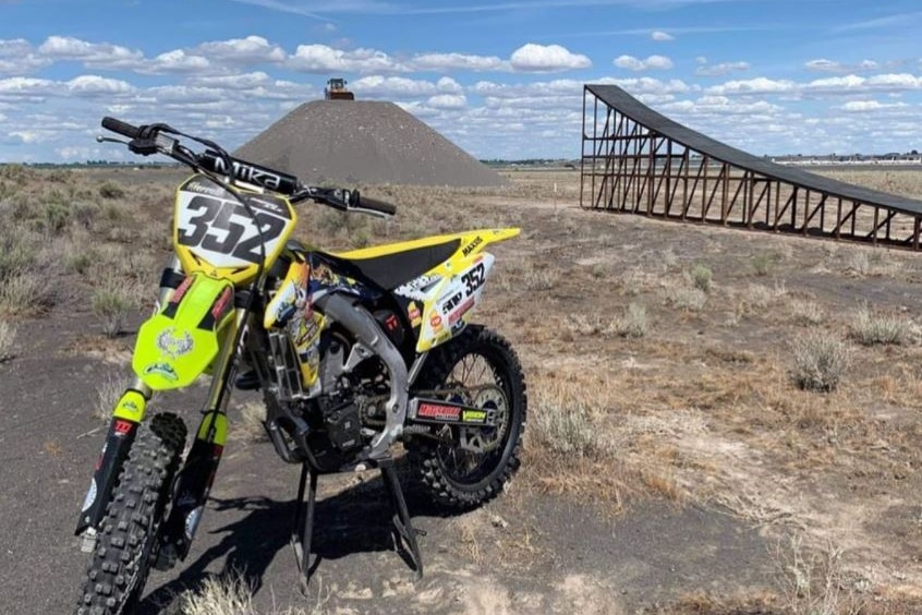 A motorcycle in front of a dirt ramp.