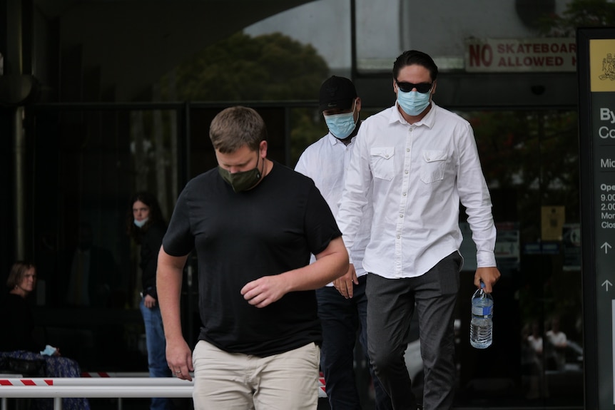 Three men walking outside court with masks on