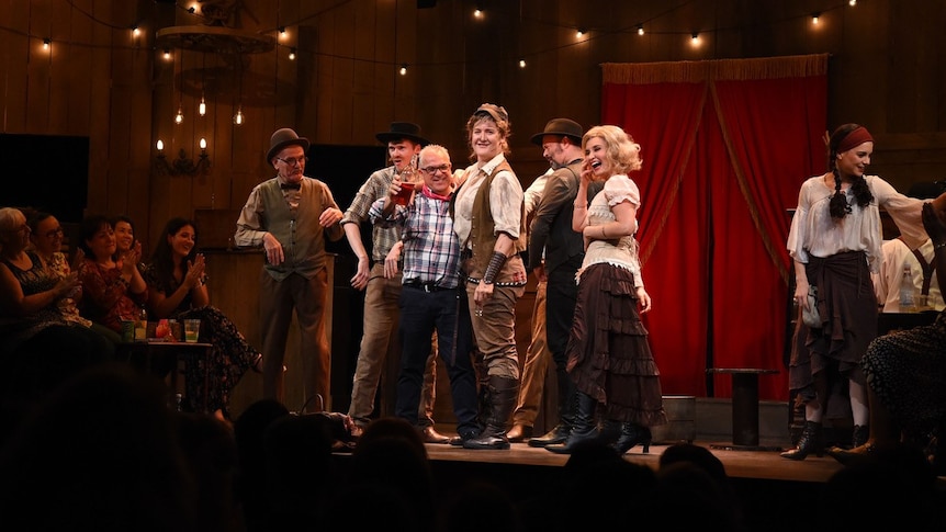 Cast members of Calamity Jane on the stage set of a wood-panelled saloon.