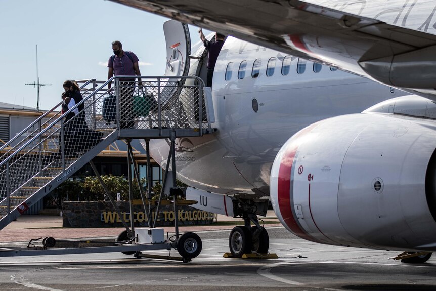 A woman holding a baby and man disembark a Qantas flight at Kalgoorlie-Boulder Airport.   