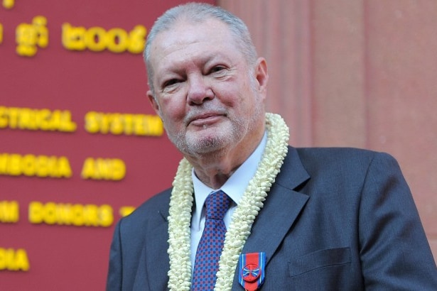 An elderly man wearing a suit, smiling at the camera