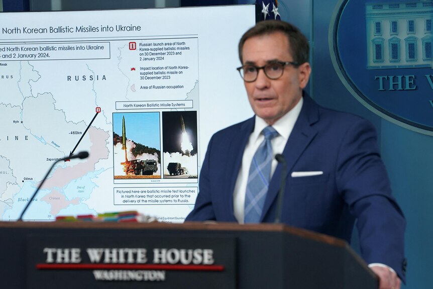 John Kirby stands at a podium at the White House in front of a graphic detailing North Korea's missiles being used by Russia