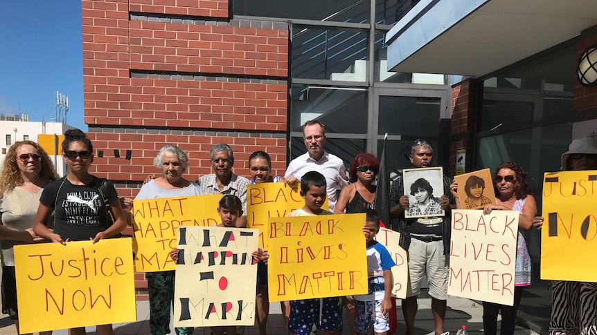 Members of the Haines family stand outside a building holding signs.