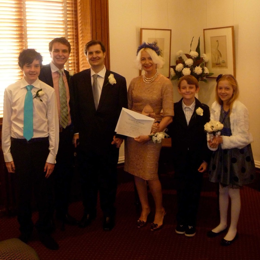 Anthony and desiree wear nice clothes alongside four children, Desiree holding their marriage certificate.