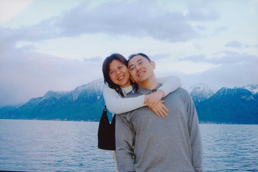Whitney Duan and Desmond Shum on a boat on a lake with mountains behind