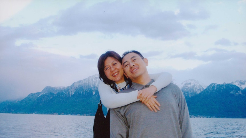 Whitney Duan and Desmond Shum on a boat on a lake with mountains behind