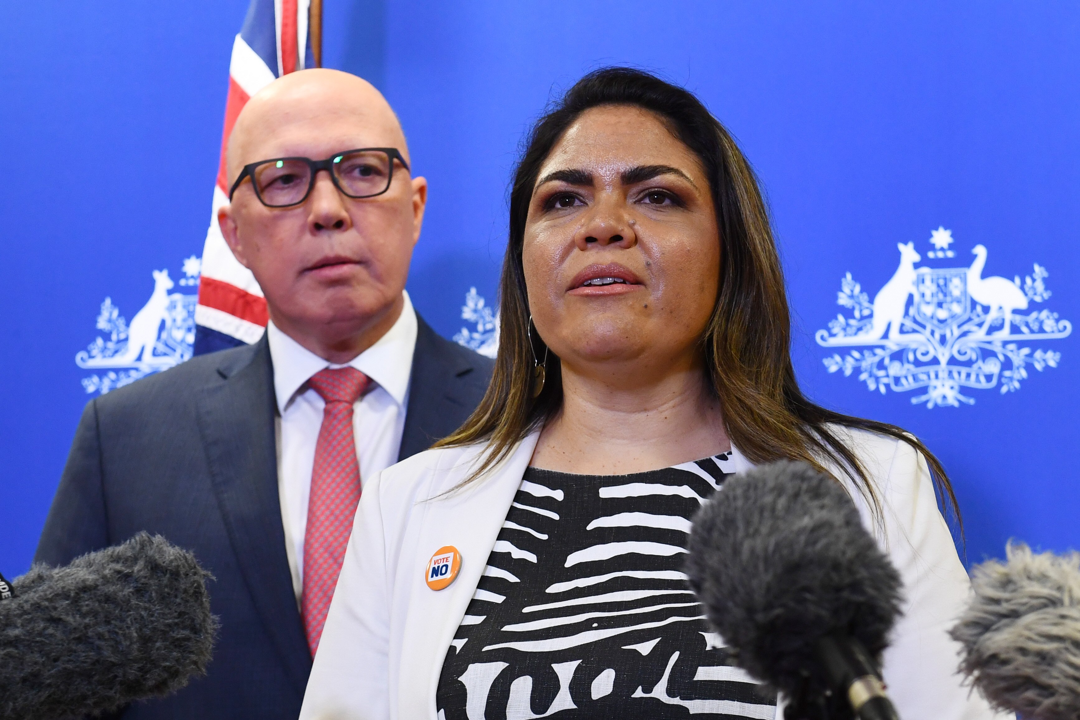 Jacinta Nampijinpa Price speaks into assembled microphones as Peter Dutton looks on.