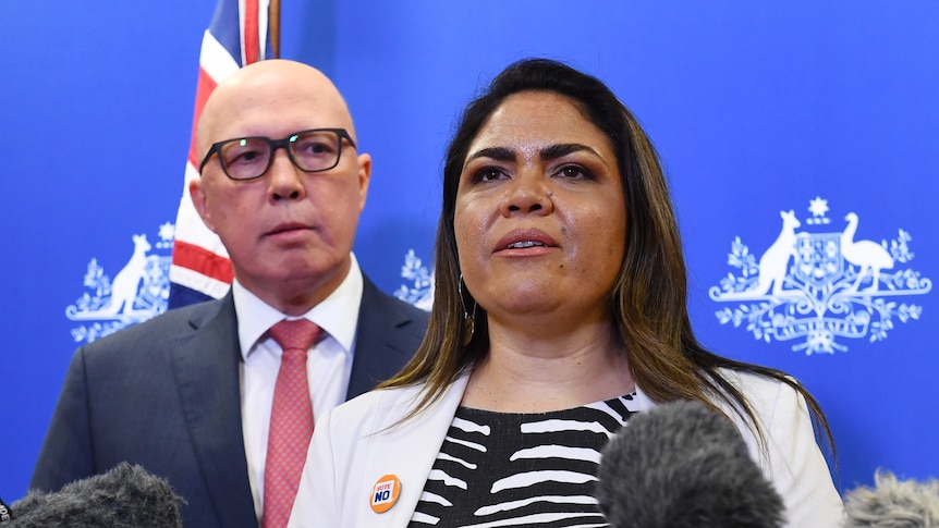 Jacinta Nampijinpa Price speaks into assembled microphones as Peter Dutton looks on.