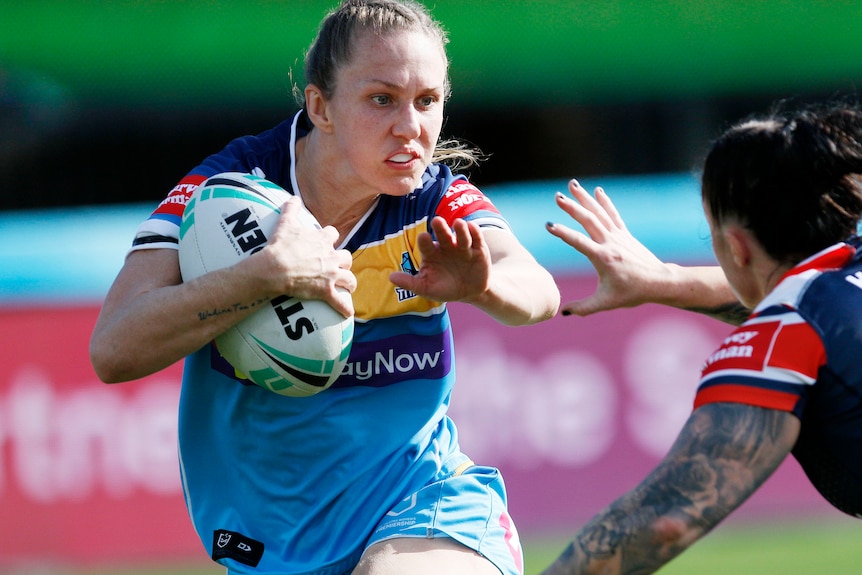 Gold Coast Titans player Karina Brown prepares to fend a player off while holding the ball