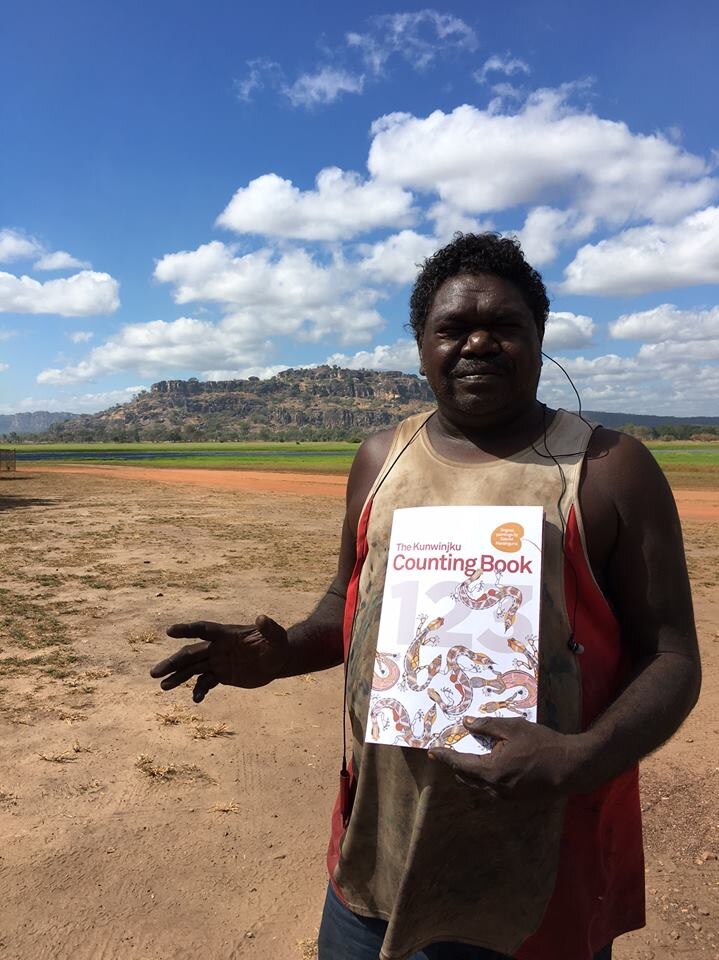 a man holding a counting book in front of lillies and hills