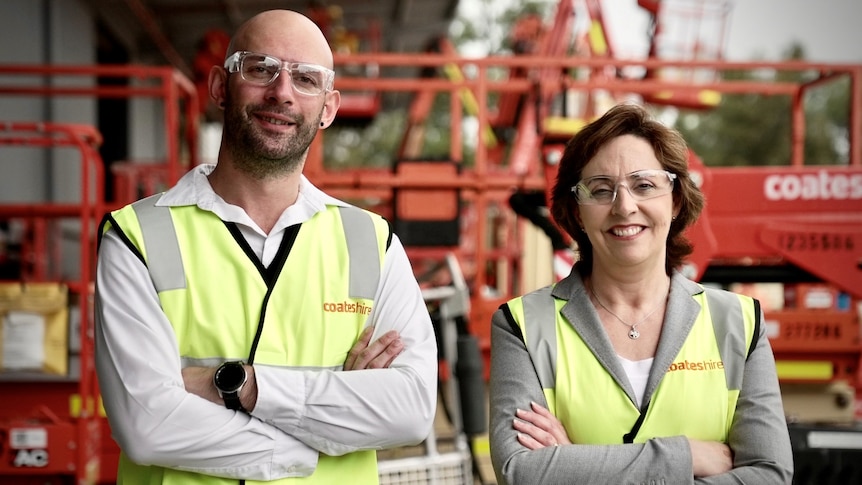 A man and a woman, both wearing safety glasses and high-vis vests