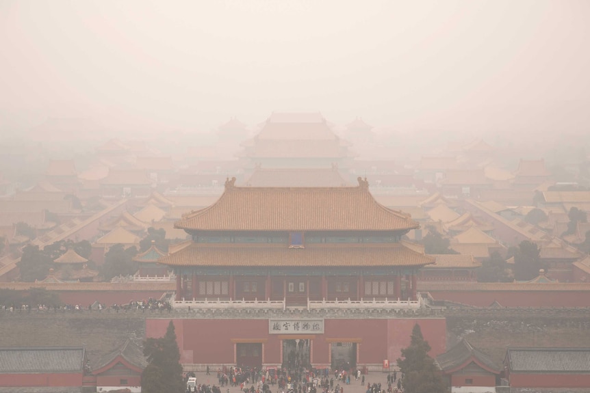 Tourists exit the Forbidden City in Beijing on a smoggy day. The photo has been taken from a high vantage point.