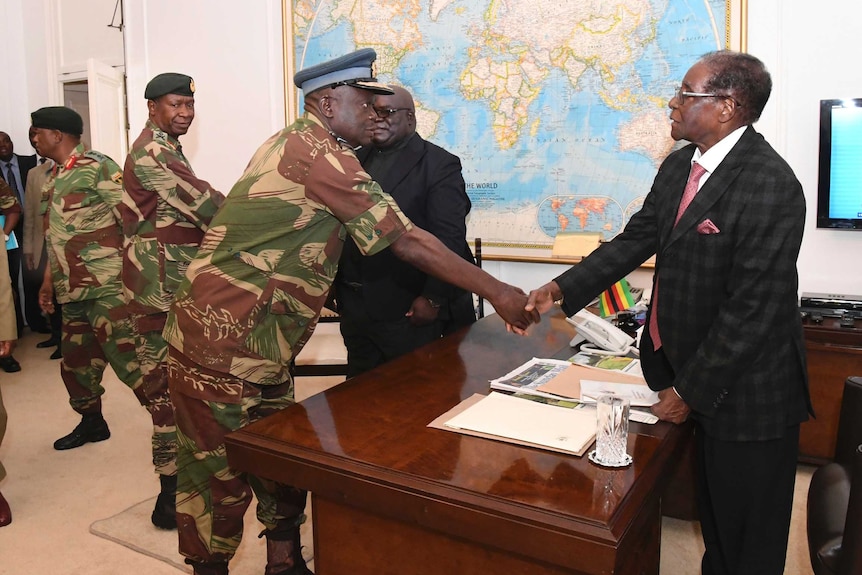 Robert Mugabe shakes hands with a military general.