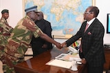 Robert Mugabe shakes hands with a military general.