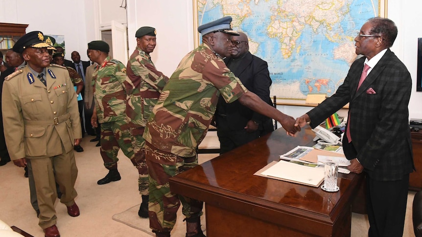 Robert Mugabe shakes hands with a military general.