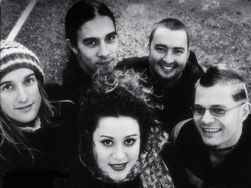 A black and white photo of a group of five people looking up at a camera and smile.