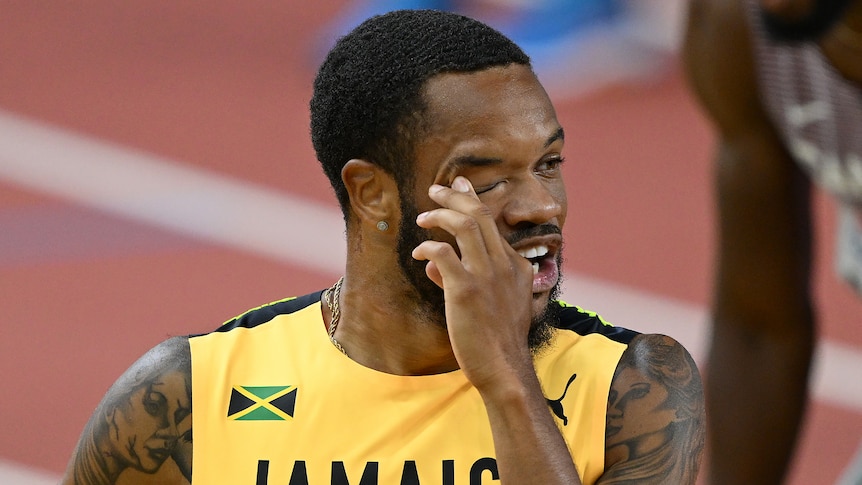 A Jamaican male sprinter touches his right eye at the World Athletics Championships.
