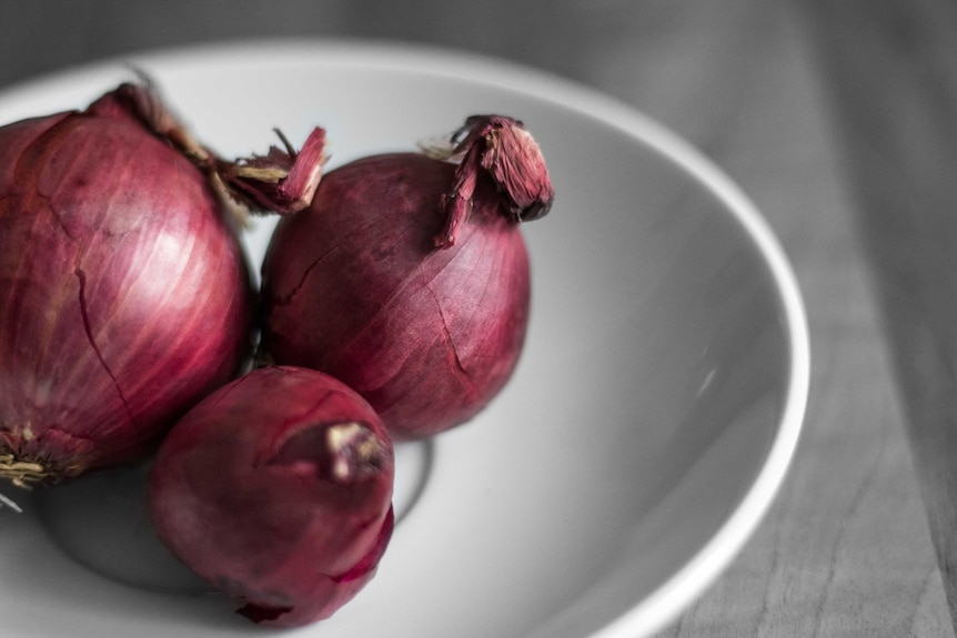 A bowl of spanish onions on a kitchen counter, pantry staples during coronavirus cooking.