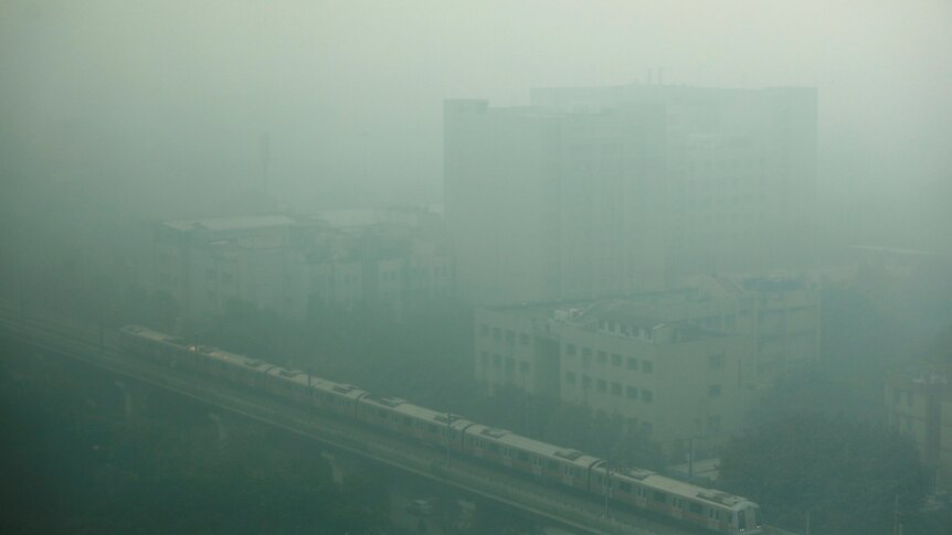 A metro train passes a hospital in heavy smog in Delhi