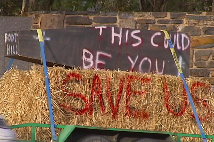 A coffin with the words "This could be you" on top of a hay bale saying "SAVE US"
