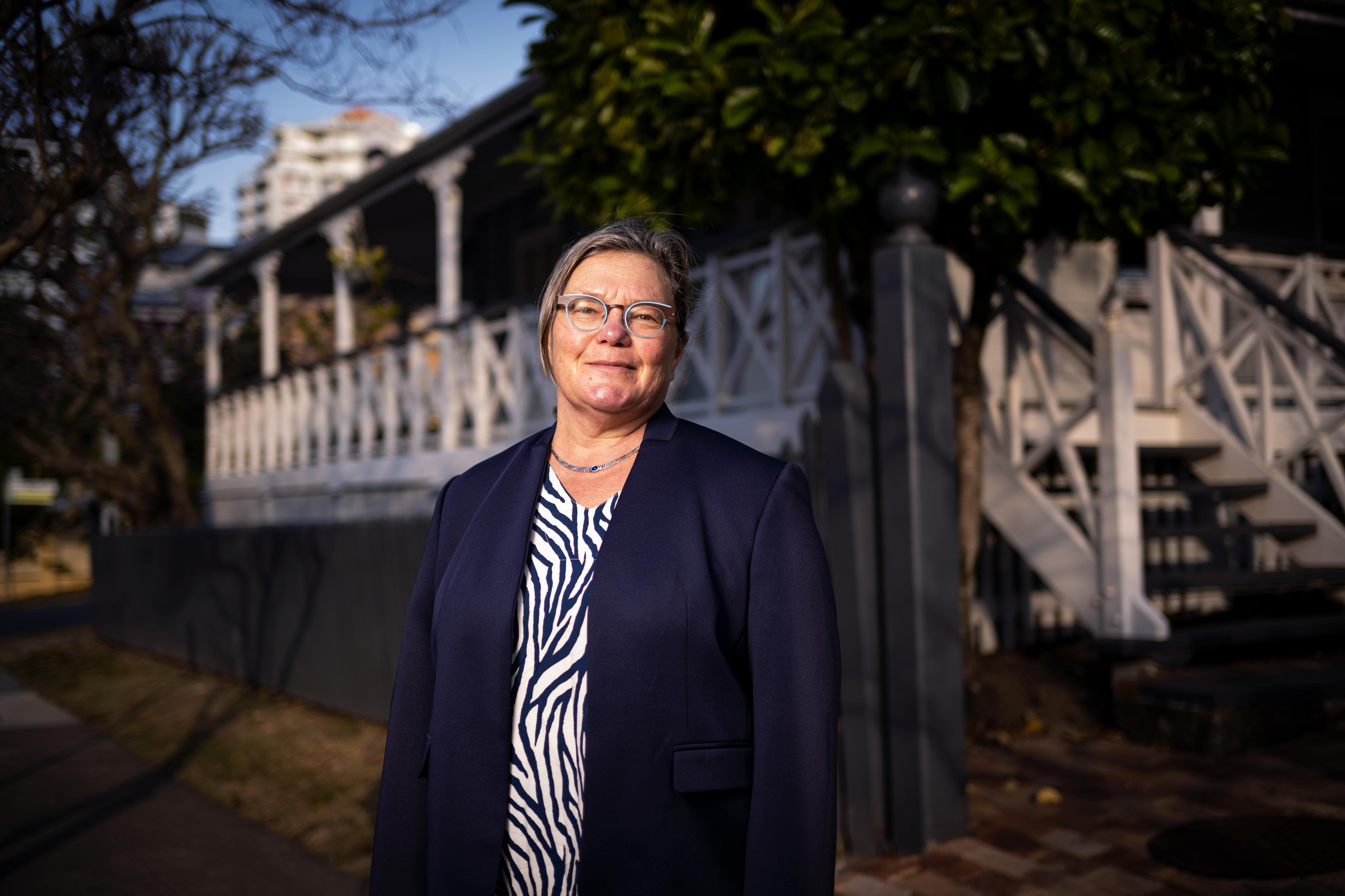 A woman in front of a Queenslander house