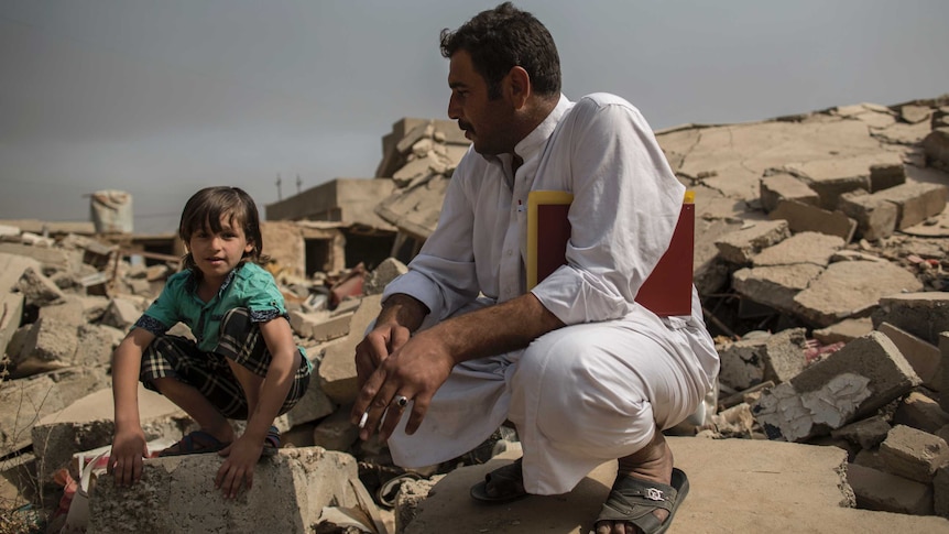 Father and son sit on the ruins of house in village of Imam Gharbi, some 70km south of Mosul.