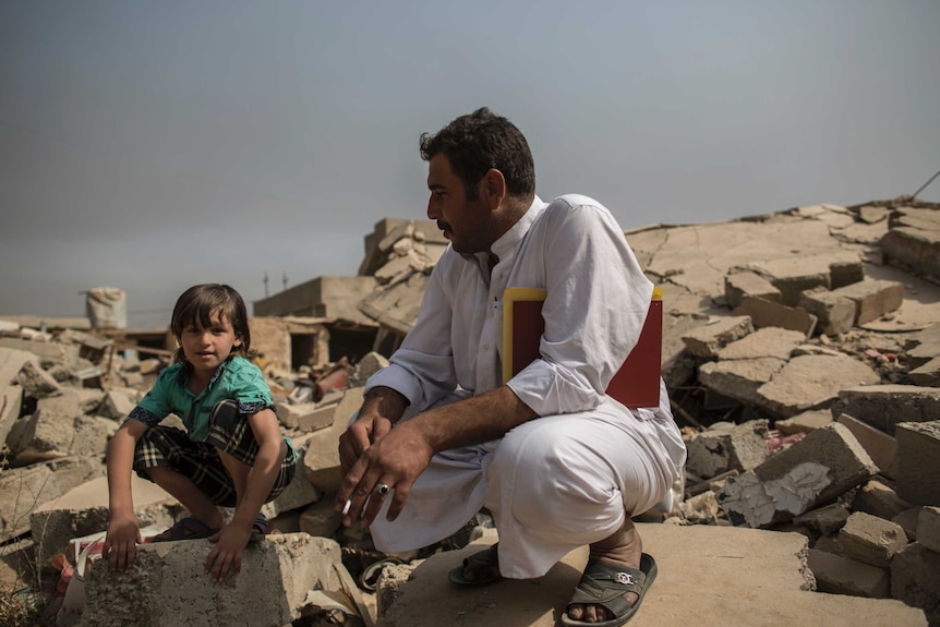 Father and son sit on the ruins of house in village of Imam Gharbi, some 70km south of Mosul.