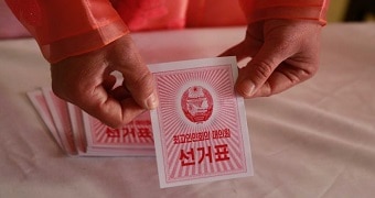 An electoral worker at a polling station in Pyongyang holds a red striped ballot during the election.