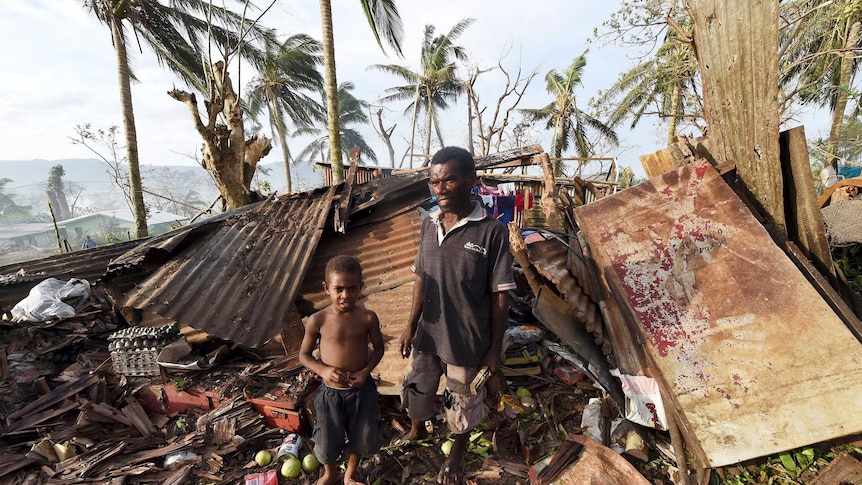 A father and son stand in the ruins of their Port Vila home