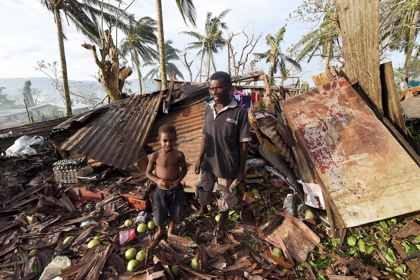 A father and son stand in the ruins of their Port Vila home