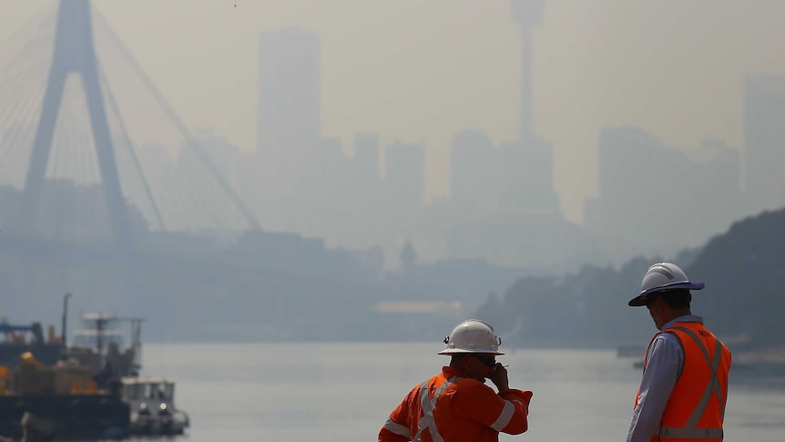 Construction workers are seen as smoke haze drifts over the CBD in Sydney in October.