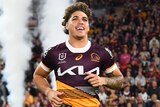 NRL player Reece Walsh runs onto a field, in front of a large crowd, to begin a match