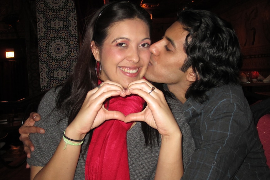 A woman makes a love heart with her hands.