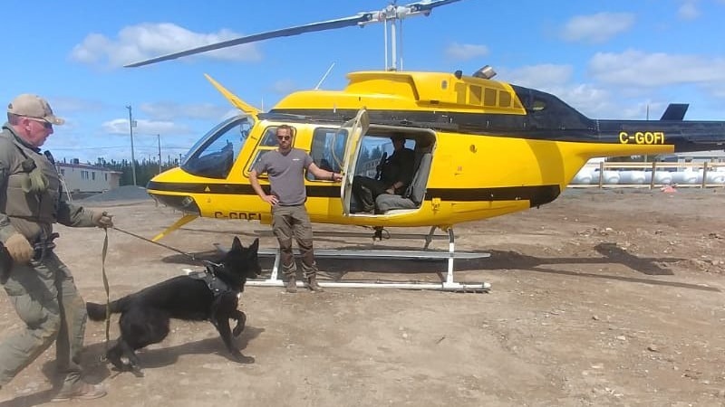 A man leading a dog to a helicopter.