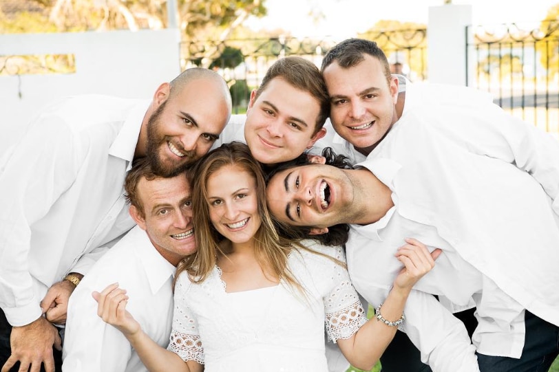 Tiana Mangakahia pictured with her five brothers, all wearing white and smiling at the camera.
