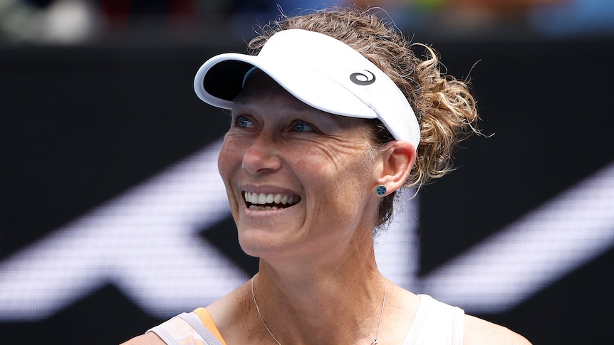 An Australian female tennis player smiles as she looks to her right at the Australian Open.