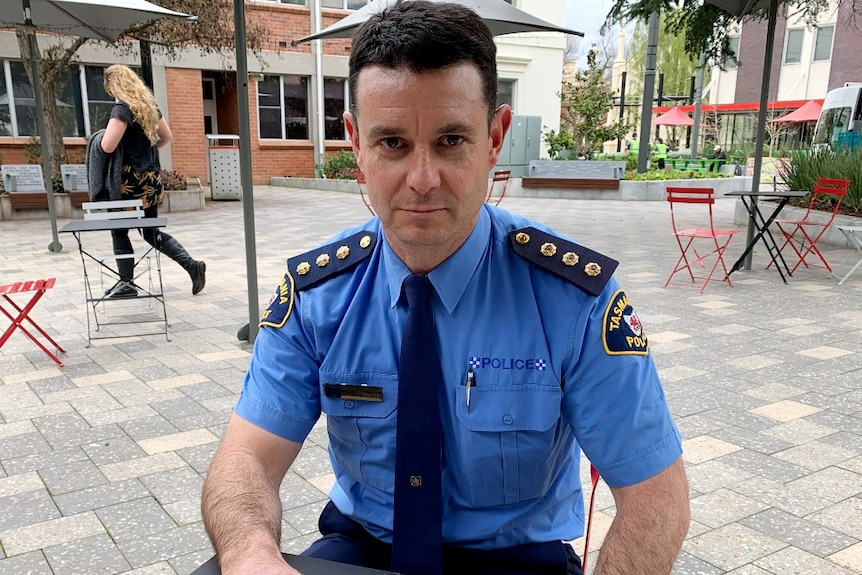 A police officer in a blue uniform sits at a table