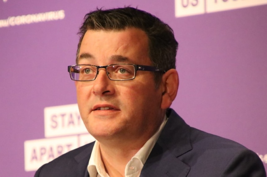 Premier Daniel Andrews delivers a press conference in front of a purple backdrop.