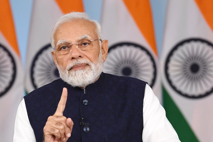 A man stands at a podium and is gesturing with one hand. 