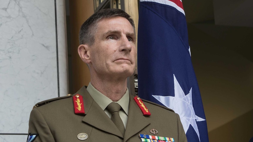 Chief of army stand in front of a flag