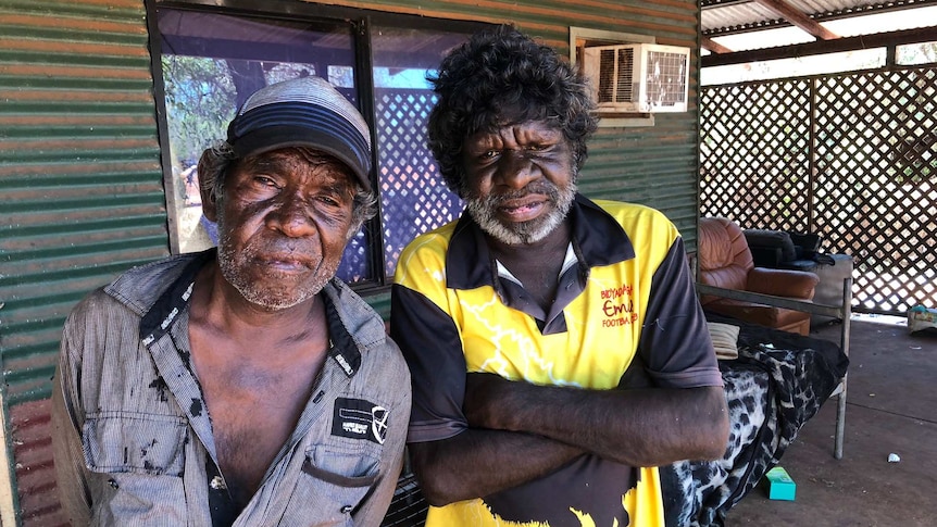 Two Indigenous men standing on the verandah of a house.