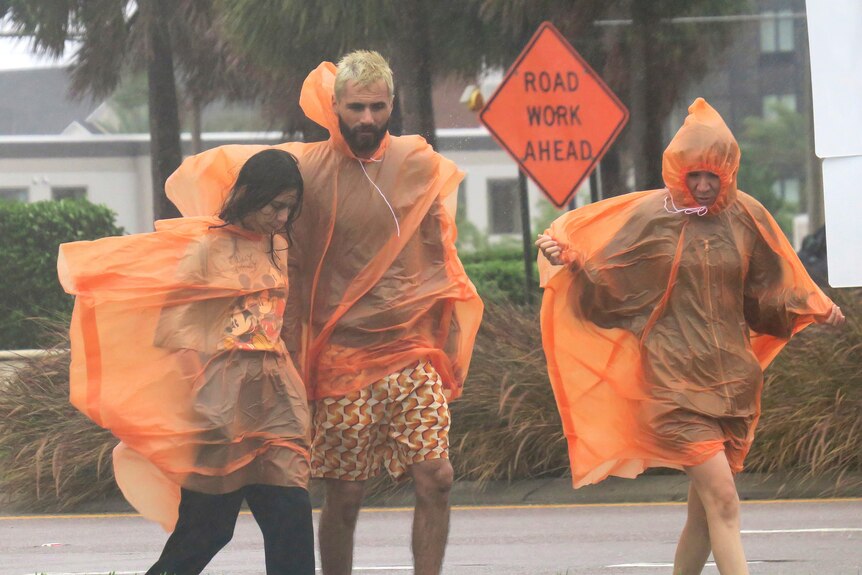 People in raincoats walk along International Drive in Orlando, Florida.