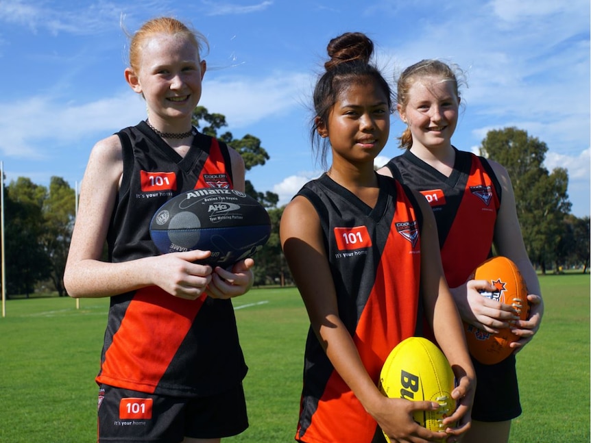 Thirteen-year-olds Briana Leary (left), Mae Cairo and Annie Kenwery in their uniforms and holding balls.
