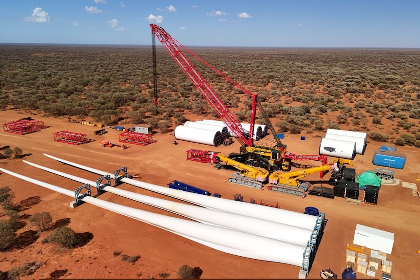 A crane being assembled at a remote mine site for construction of wind turbines with blades laying on the ground.  