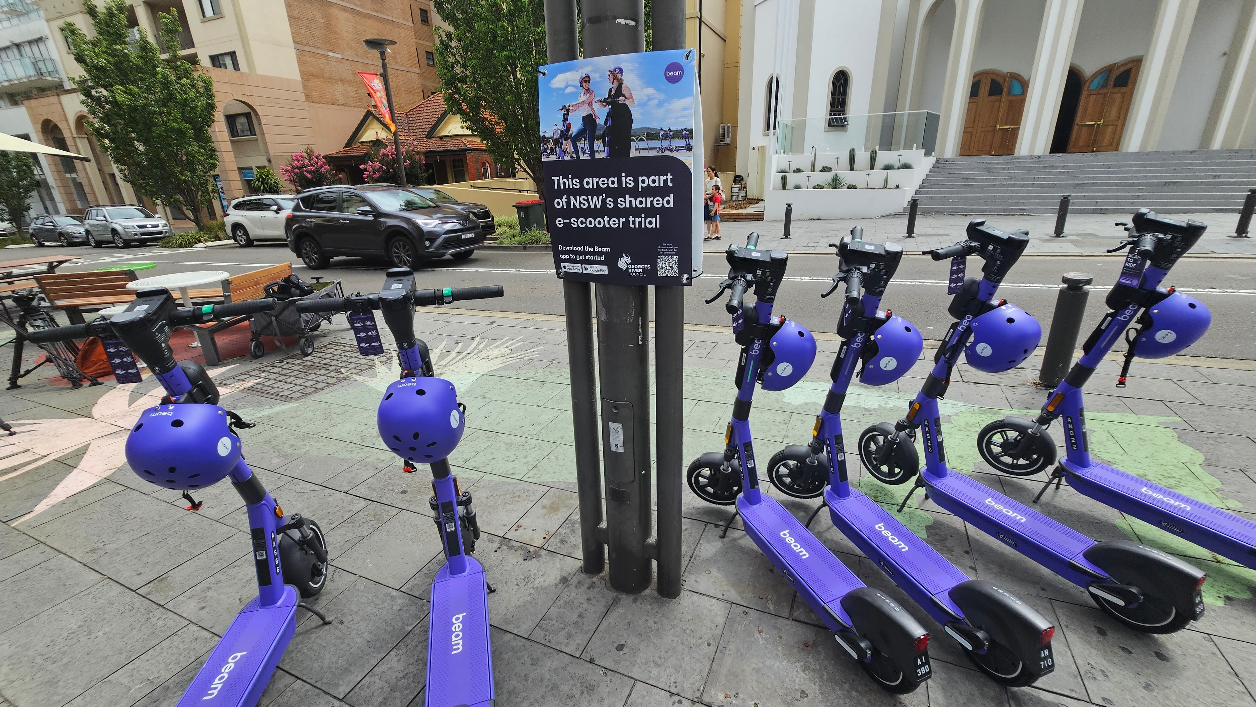 A row of purple scooters by the side of a road