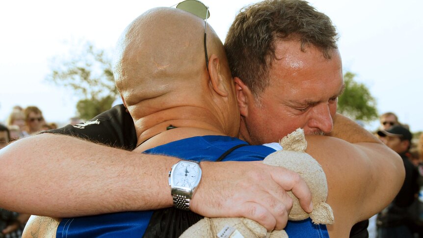 Father is consoled during memorial.