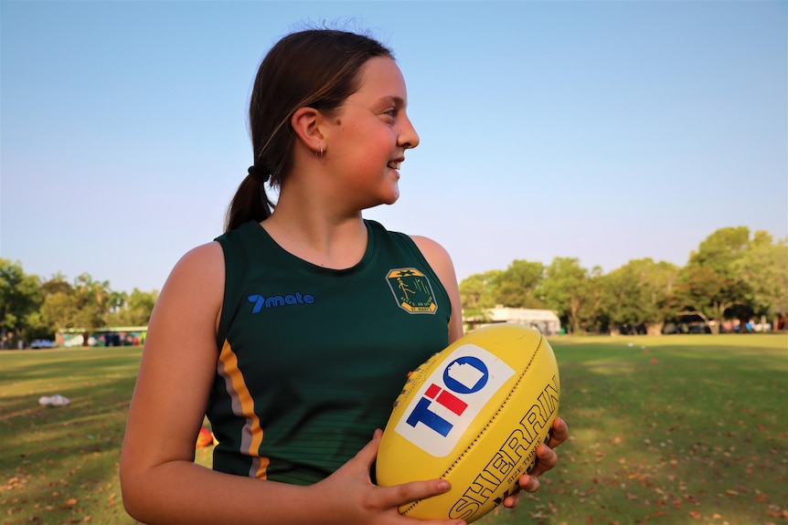 Isabell Dewsbury looks away from the camera holding a football wearing a St Mary's singlet at Nightcliff oval.