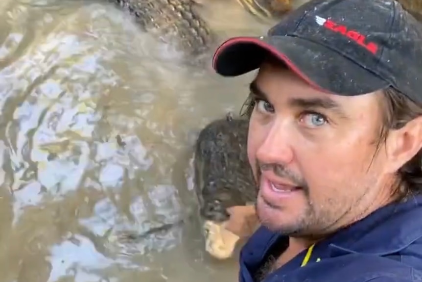 Matt Wright's hands are in murky water near the mouth of a 4m croc.